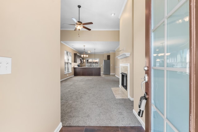 unfurnished living room featuring baseboards, a fireplace with flush hearth, ceiling fan, ornamental molding, and carpet flooring