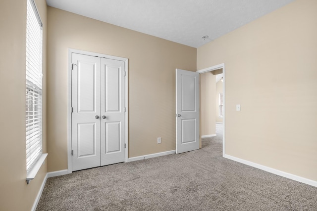 unfurnished bedroom with a closet, carpet flooring, and baseboards