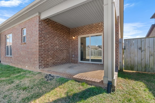 property entrance featuring brick siding, a patio, and fence