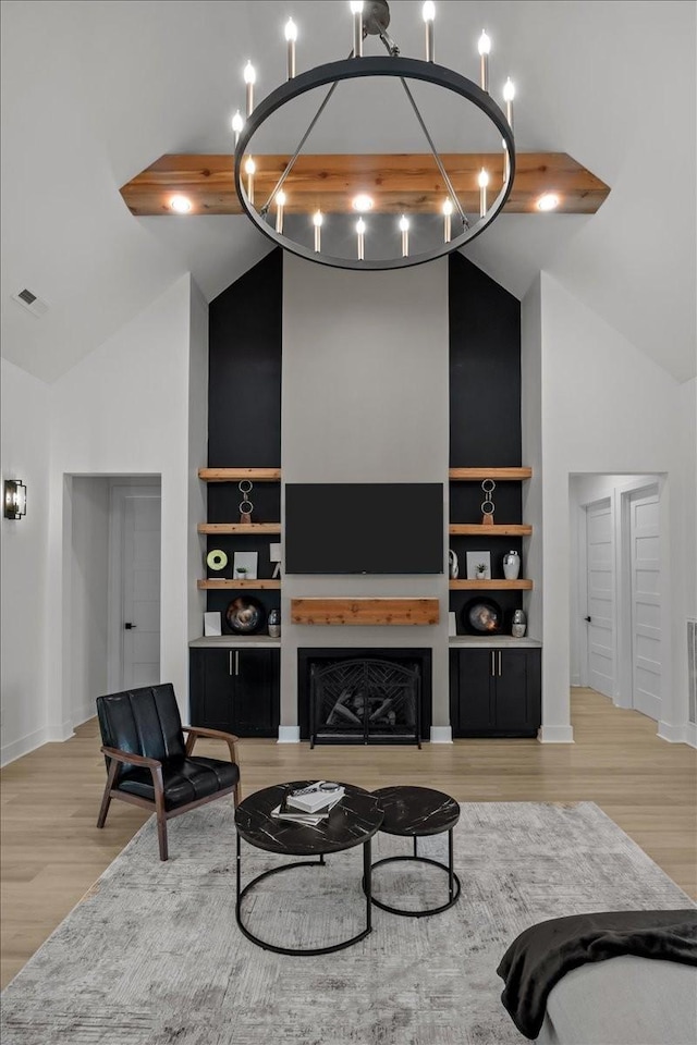 living area with built in features, a fireplace, high vaulted ceiling, and light wood finished floors