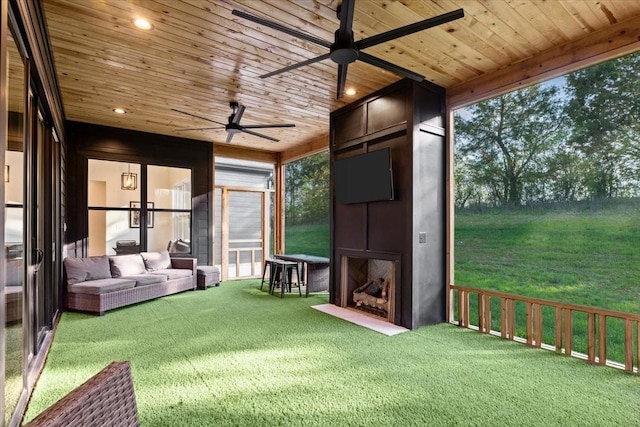 unfurnished sunroom with a large fireplace, wood ceiling, and a ceiling fan