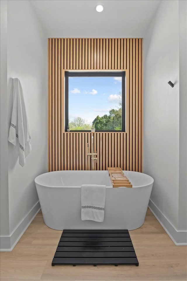 full bath featuring a freestanding tub, baseboards, and wood finished floors