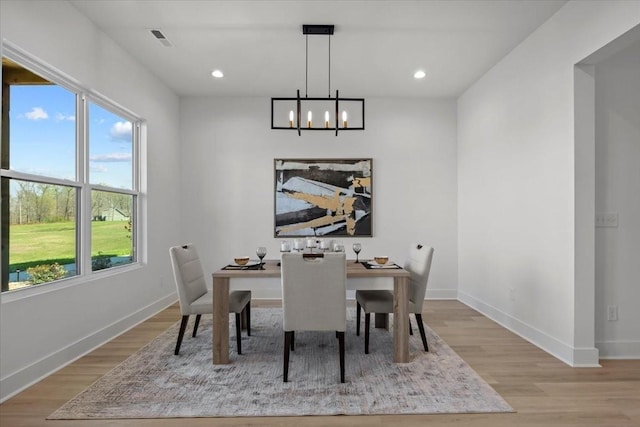 dining room featuring light wood-style flooring, visible vents, and baseboards