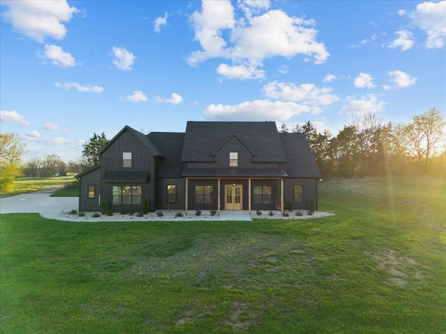 rear view of property with board and batten siding and a lawn