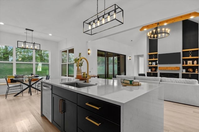 kitchen with light stone counters, hanging light fixtures, a sink, an island with sink, and a chandelier