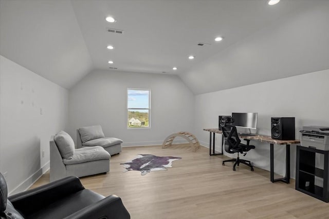 home office with visible vents, vaulted ceiling, and light wood-style flooring