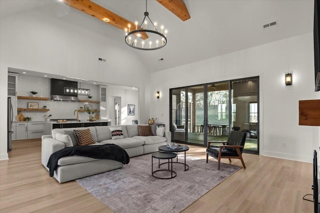 living area with high vaulted ceiling, visible vents, a chandelier, light wood-type flooring, and beamed ceiling