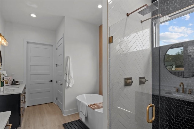 full bathroom with recessed lighting, a soaking tub, vanity, a shower stall, and wood finished floors