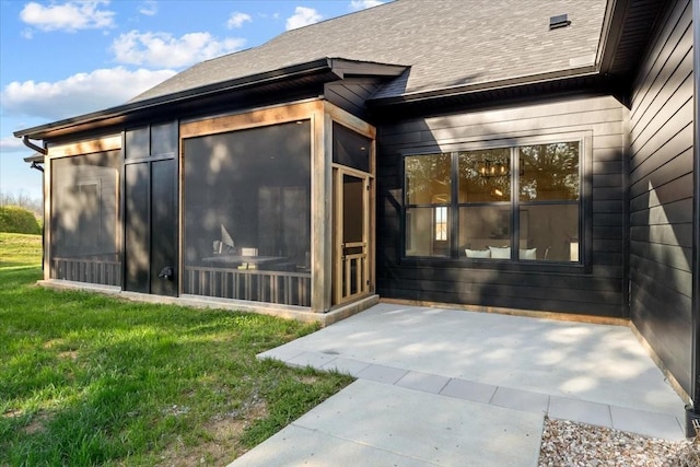 entrance to property featuring a patio area, a shingled roof, and a yard