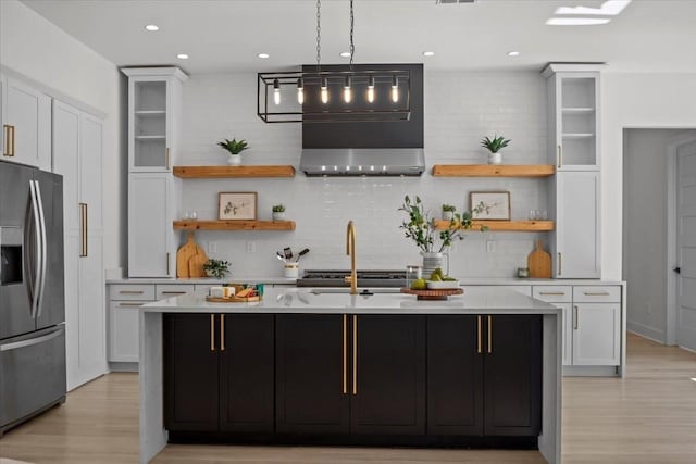 kitchen featuring light countertops, open shelves, stainless steel fridge, and glass insert cabinets