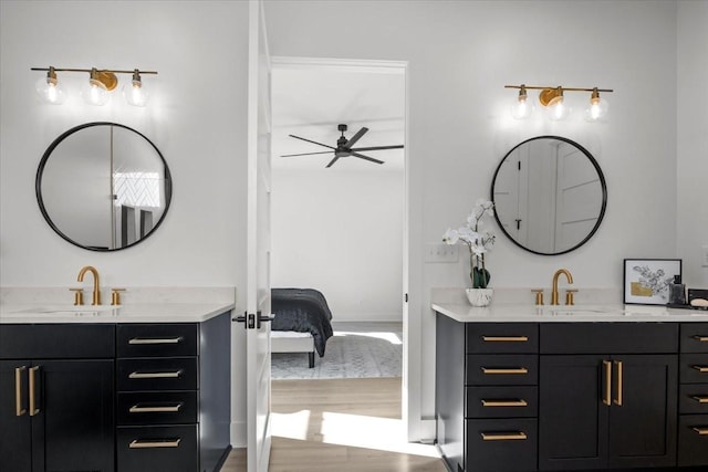 bathroom with wood finished floors, ensuite bath, two vanities, and a sink