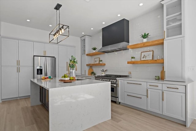 kitchen with a center island, stainless steel appliances, light countertops, wall chimney range hood, and open shelves