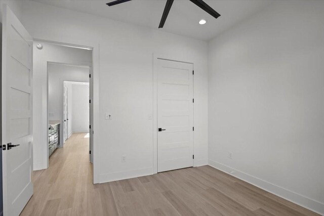 unfurnished bedroom featuring a ceiling fan, a closet, light wood-style flooring, and baseboards