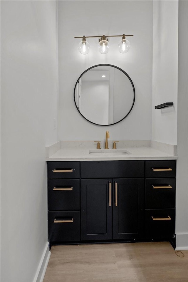 bathroom with baseboards, wood finished floors, and vanity