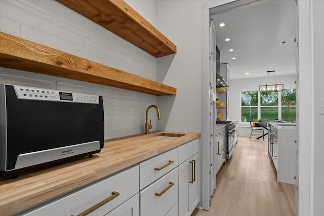 bar featuring high end stove, recessed lighting, a sink, light wood-style floors, and decorative backsplash