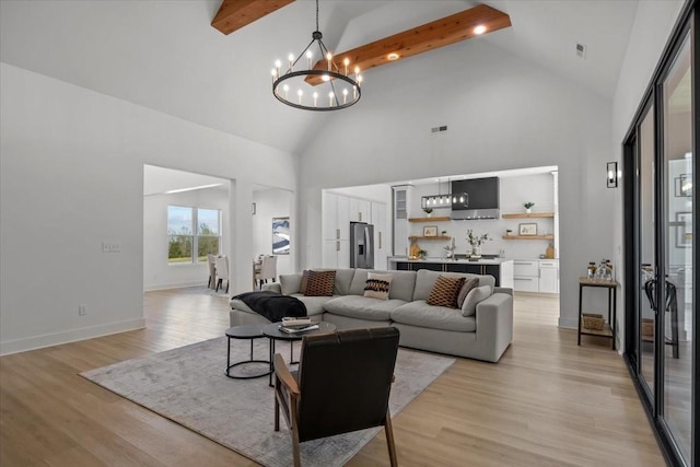 living area with light wood-style floors, a notable chandelier, and beam ceiling