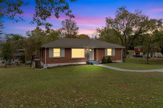 view of front facade with brick siding and a yard