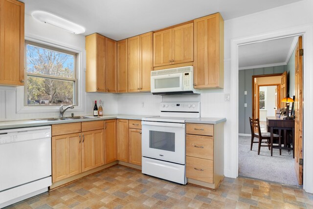 kitchen with light countertops, light brown cabinetry, stone finish flooring, a sink, and white appliances