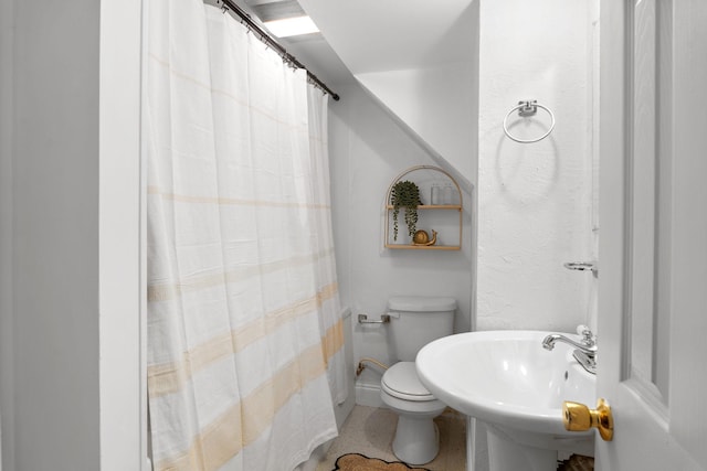 bathroom featuring a shower with shower curtain, a sink, and toilet