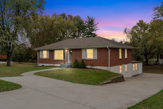 ranch-style home with driveway, a lawn, and brick siding