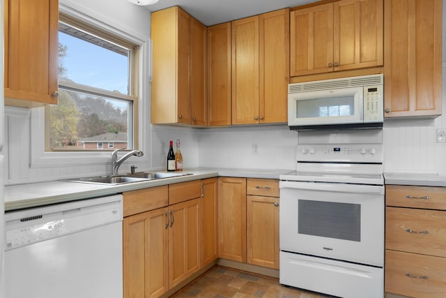 kitchen featuring white appliances, light countertops, and a sink