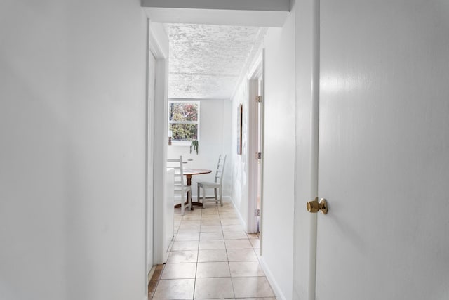 corridor featuring a textured ceiling and light tile patterned flooring