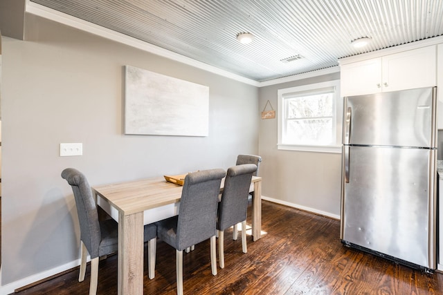 dining room featuring dark wood-style floors, crown molding, and baseboards