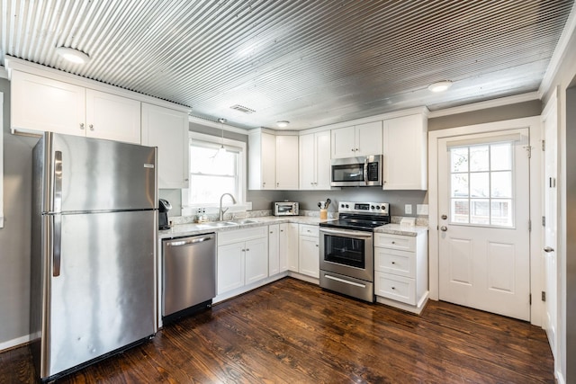 kitchen with light stone counters, dark wood-style floors, stainless steel appliances, white cabinets, and a sink