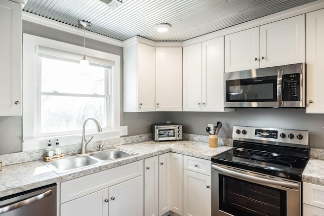 kitchen with pendant lighting, stainless steel appliances, a sink, and white cabinets