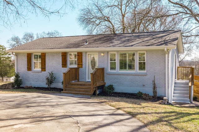 single story home featuring driveway, brick siding, and a shingled roof