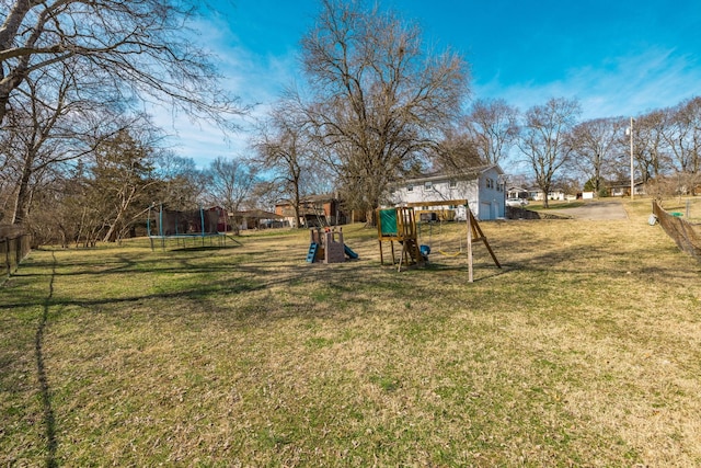 view of yard with a garage, a trampoline, and a playground