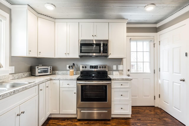 kitchen with stainless steel appliances, a toaster, white cabinets, and dark wood-style floors