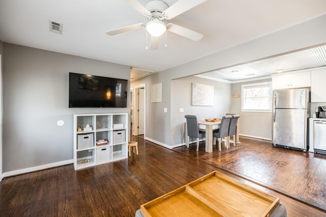 unfurnished living room with a ceiling fan, visible vents, baseboards, and wood finished floors