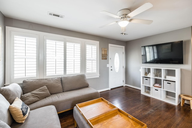 living room with dark wood-style floors, ceiling fan, visible vents, and baseboards