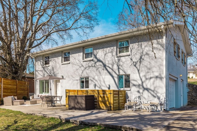 back of property with an attached garage, fence, and brick siding