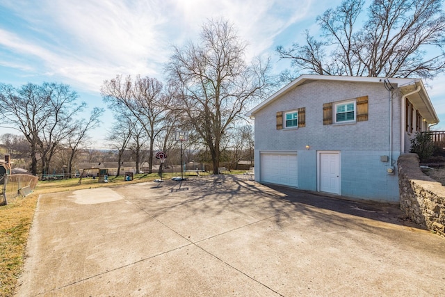 view of property exterior featuring concrete driveway, brick siding, and an attached garage