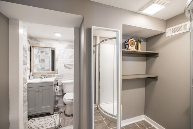 full bathroom featuring tile walls, visible vents, a stall shower, vanity, and baseboards