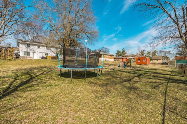 view of yard with a trampoline, fence, and a playground