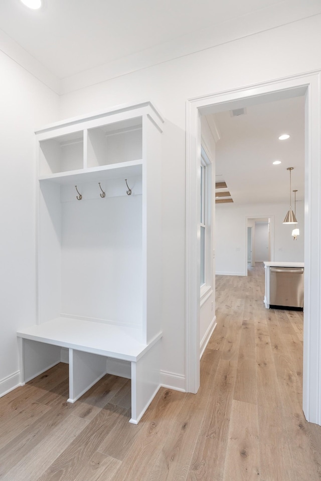 mudroom with light wood-style floors, crown molding, and baseboards