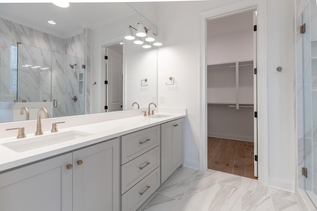 bathroom with marble finish floor, a marble finish shower, a walk in closet, and a sink