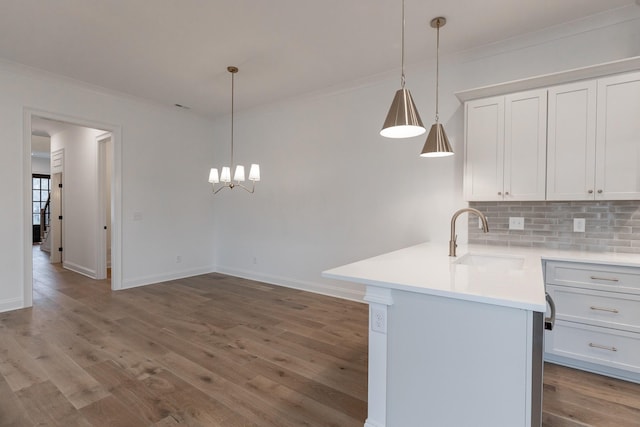 kitchen featuring a sink, white cabinetry, light countertops, tasteful backsplash, and crown molding