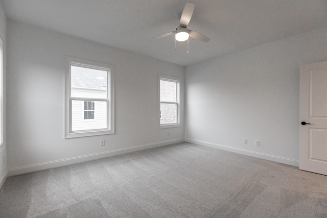 unfurnished room with a ceiling fan, light colored carpet, and baseboards