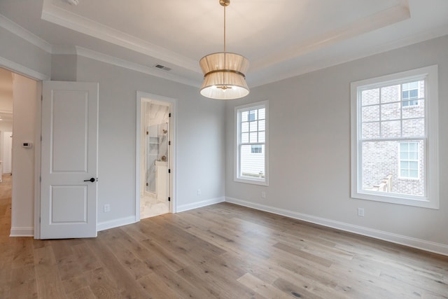 unfurnished room with wood finished floors, visible vents, baseboards, ornamental molding, and a tray ceiling