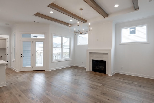 unfurnished living room featuring plenty of natural light, a fireplace, beam ceiling, and wood finished floors