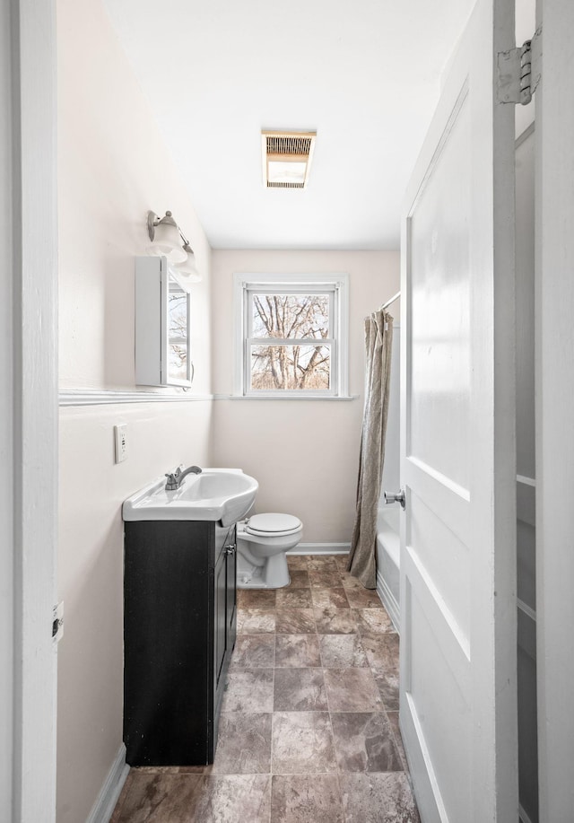 bathroom with visible vents, toilet, shower / tub combo, vanity, and baseboards