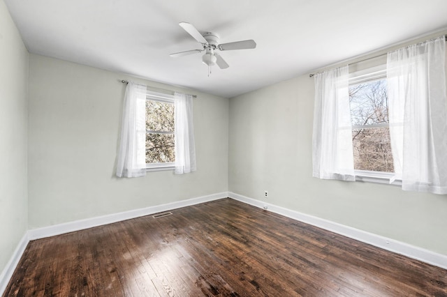 unfurnished room featuring ceiling fan, dark wood finished floors, visible vents, and baseboards