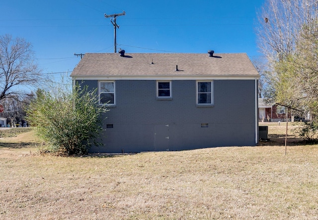 exterior space featuring a yard, roof with shingles, and brick siding