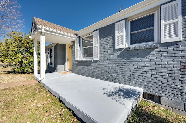 view of property exterior featuring brick siding and roof with shingles