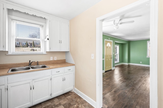 kitchen featuring baseboards, white cabinets, ceiling fan, light countertops, and a sink