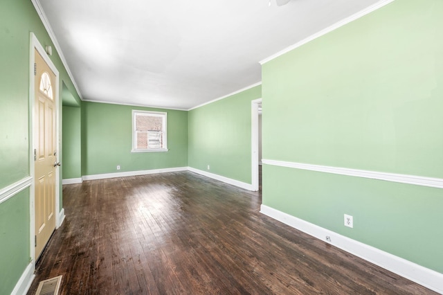 spare room with dark wood-style floors, visible vents, crown molding, and baseboards